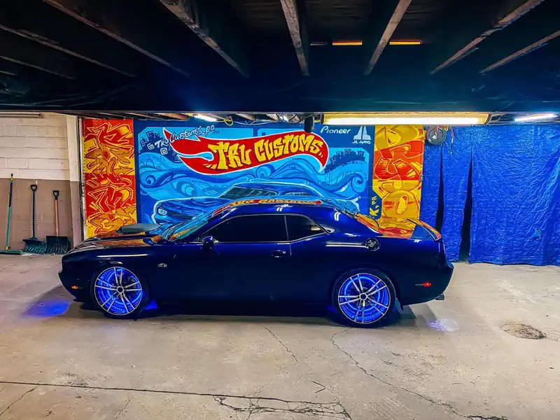 Dark blue Dodge Challenger side view with glowing blue LED wheel rings
