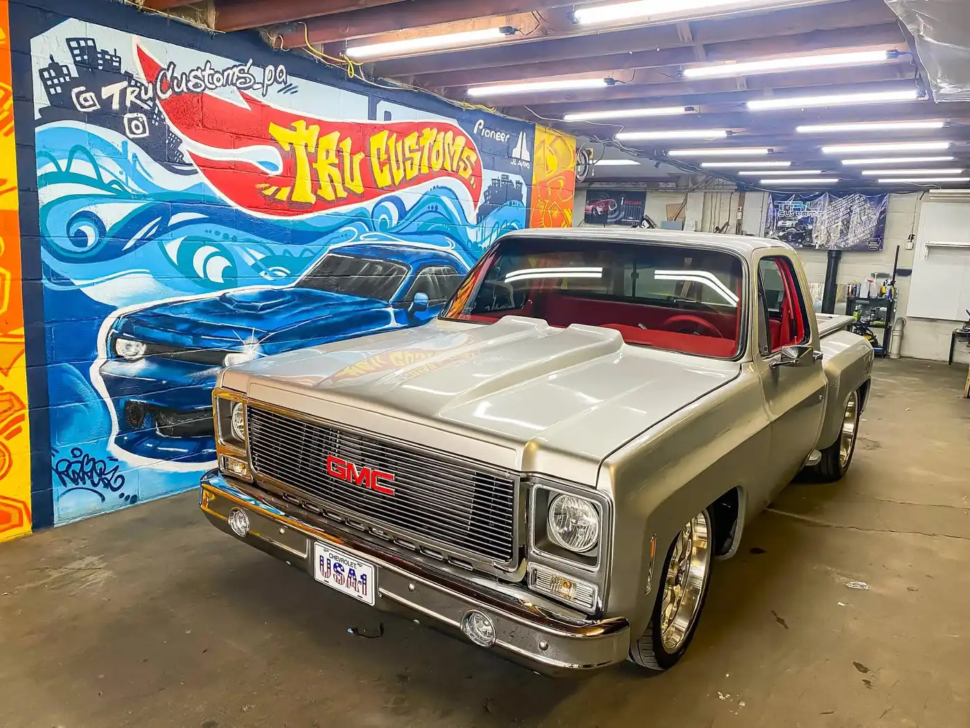 Silver classic GMC square-body pickup with a red interior and polished wheels